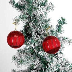 Red Christmas ornaments with sequins hanging on snowy tree branches set of two
