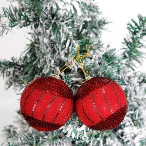 Sparkling red sequin Christmas ball ornaments with stripes on a snowy festive tree
