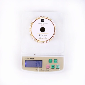 Detailed view of 6.3cm wide Christmas sheer ribbon roll weighing 34g on a digital scale
