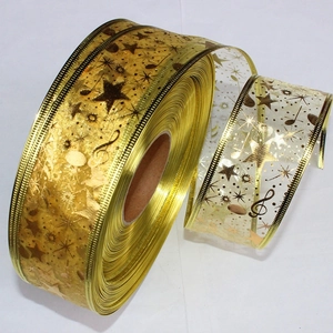 Detail of 10m gold Christmas ribbon with star and musical note patterns for gift wrapping
