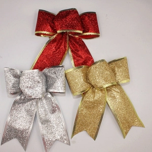 Three glittering Christmas ribbon bows in red, gold, and silver with metallic gold edging