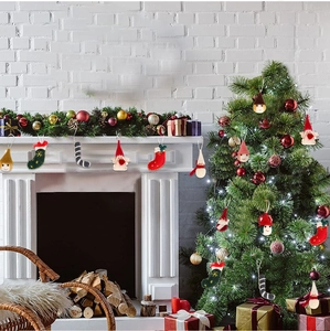 Detail of felt Christmas gnome, stocking and angel ornaments on a warm fireplace mantle