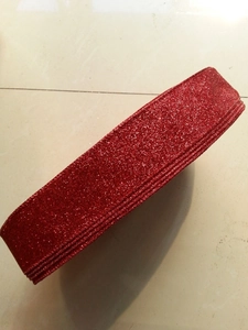Close-up of red glitter ribbon roll with sparkling texture for Christmas gift wrapping
