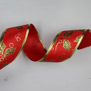 Close-up of red Christmas ribbon with golden edges and festive holly berry pattern