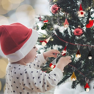 Felt Christmas doll ornaments and mini socks hanging on a festive decorated tree