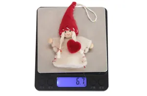 Detail of a handmade felt Christmas doll ornament weighing 6.7g on a digital scale
