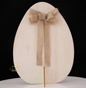 Dettaglio decorazione uovo di Pasqua in legno con venature naturali e fiocco in iuta