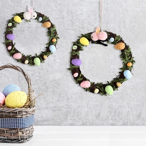 Close-up of Easter rattan wreath with colorful speckled eggs and plush rabbit ears