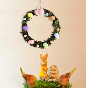 Easter wreath with pastel eggs and a plush bunny next to a Frohe Ostern resin figurine