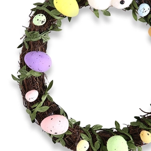 Easter wreath with natural rattan base colorful eggs and green leaves for door decor