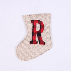 Detail of Christmas stocking decoration made of beige linen with red and black plaid letter R