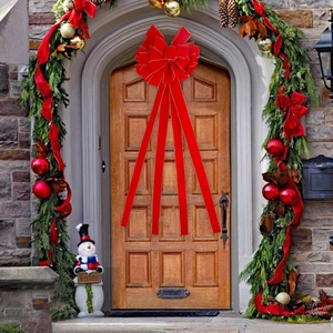 Détail d'un nœud de Noël en velours rouge avec bordure dorée sur une porte festive