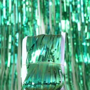 Detail of green metallic foil fringe curtain folded on white cardboard for party decor