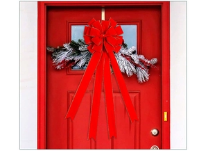 Close-up of velvet red Christmas bow with golden glitter edges and snowy pine branch
