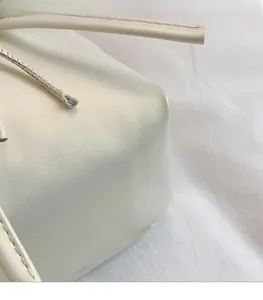 Detailed macro view of cream PU leather texture and neat stitching on a women handbag