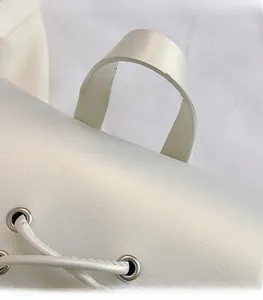 Detailed macro view of white PU leather texture with silver grommets and sturdy handle attachment
