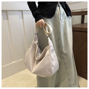 Close-up of a cream nylon hobo bag showing soft texture and adjustable strap detail