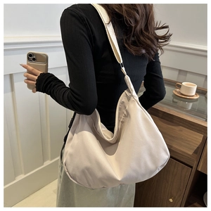 Detail of minimalist beige half-moon tote bag with a wide fabric shoulder strap