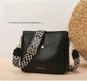 Close-up of black crossbody bag with geometric wide strap and gold hardware details