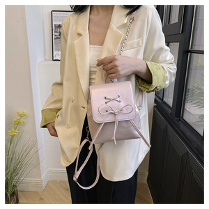 Chic pink PU leather mini backpack with ribbon bow detail on casual model outfit