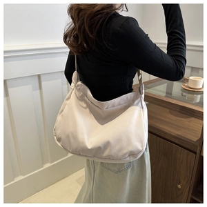 Close-up of a minimalist beige hobo bag with adjustable shoulder strap and zipper closure