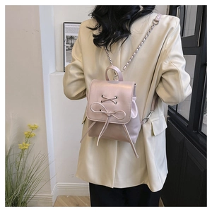 Mini pink PU leather backpack with chain strap and bow detail on female model
