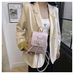 Close-up of a mini pink PU leather backpack featuring bow detail and metal chain strap