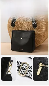 Detailed macro view of high-quality golden metal hardware on a black crossbody bag