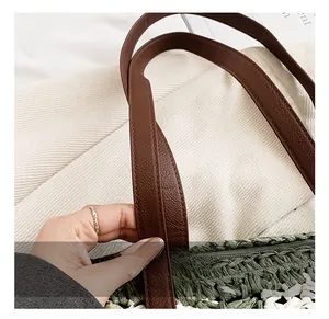 Close-up of brown leather handle and green woven straw tote bag craftsmanship details