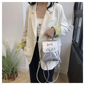 Detail of silver metallic PU leather mini backpack with drawstring and bow decoration