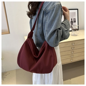 Detail view of large burgundy high-density nylon shoulder bag with a crescent shape design