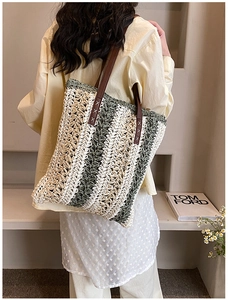 Detail view of large woven tote bag with green stripes and brown leather handles