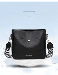 Detail of black pebbled polyester crossbody bag with gold buckle and wide geometric strap