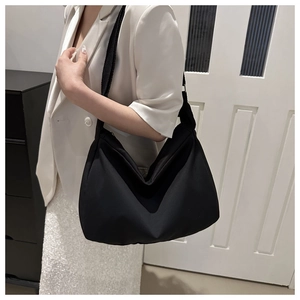 Chic black nylon hobo bag styled on model with white blazer and sequin skirt