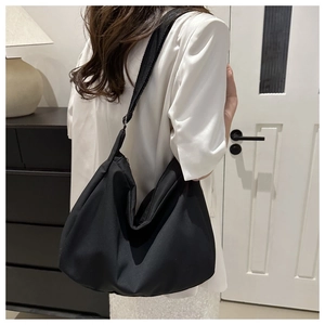 Detail view of a black nylon tote bag on a model showing spacious interior and wide strap