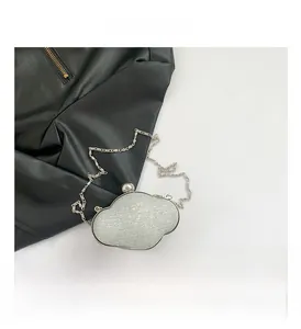 Detail of silver cloud clutch bag with glitter texture and elegant metal ball clasp