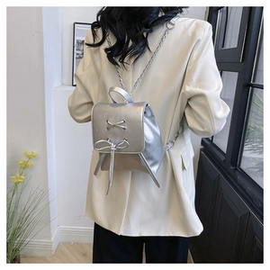 Silver PU leather mini backpack featuring cross straps, bow detail, and a slim chain strap