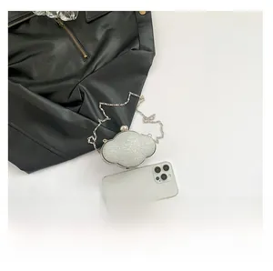 Mini silver glitter cloud clutch bag shown next to a smartphone for size comparison