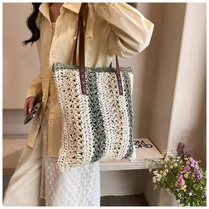 Close-up of woven straw texture and leather straps with cross-stitching on tote bag