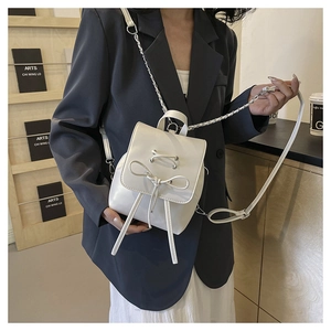 Detail of white PU leather mini bag with bow tie and adjustable silver chain strap