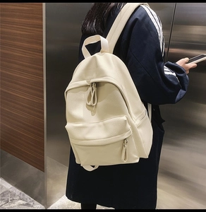 Close-up of cream white backpack in litchi grain faux leather worn by a model