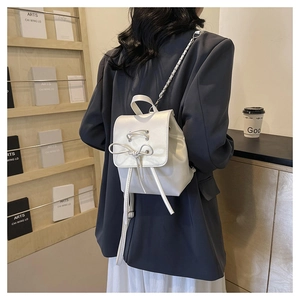 Close-up of a cream white PU leather mini backpack with bow detail and chain straps