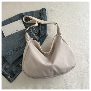 Minimalist beige moon-shaped hobo bag with adjustable wide fabric strap and zipper top