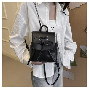 Detail of black PU leather mini backpack with stylish bow lace-up and metallic eyelets