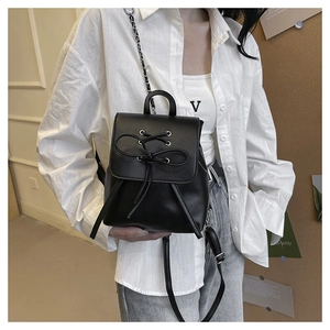 Detail of black PU leather mini backpack with bow decoration and chain straps