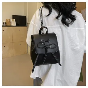 Detail of a black PU leather mini backpack with lace-up bow and metal chain strap