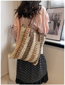Detail of multi-color woven straw tote bag with reinforced leather shoulder straps