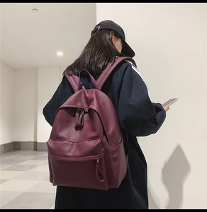 Detailed back view of a dark burgundy pebbled leather backpack with adjustable shoulder straps