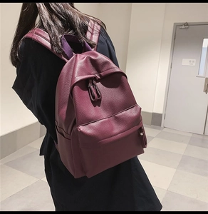 Detail view of burgundy leather backpack with litchi texture and padded shoulder straps