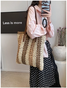 Detail view of the woven straw tote bag with brown leather straps and vertical stripes